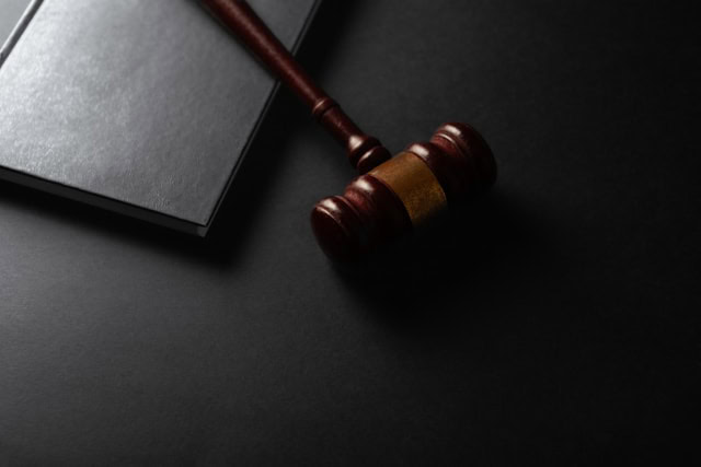 wooden gavel resting on a dark surface next to book